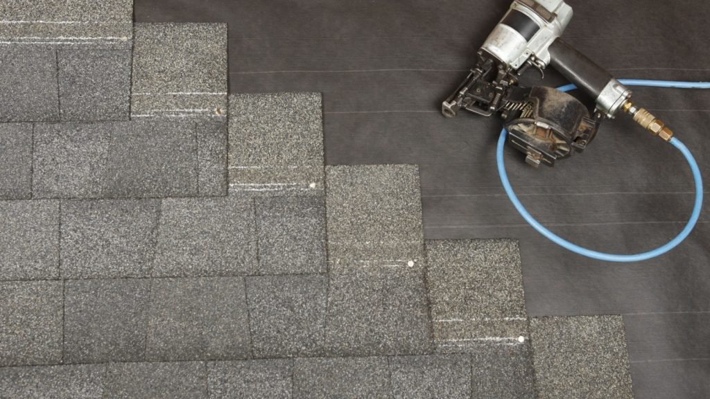 A new roof partially installed with nail gun in frame.