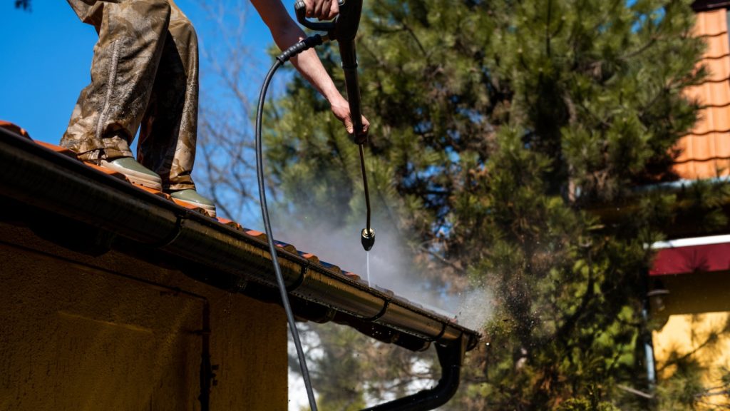 Bumble Roofing power washing gutters for their roofing maintenance program.