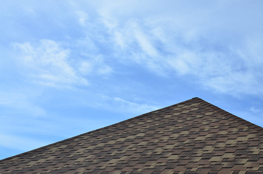 Shingle roof foreground a blue sky during a cloudless day in The Woodlands, TX.
